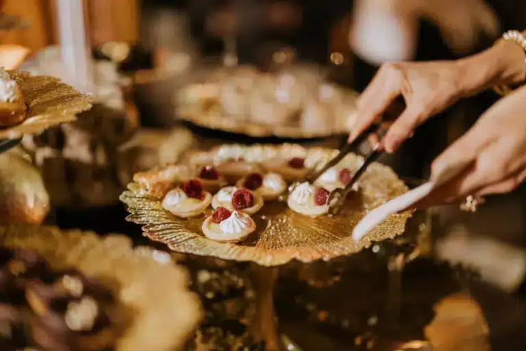 Guests at an event atered by Betty ZLatchin use tongs to remove appetizers from a golden tray
