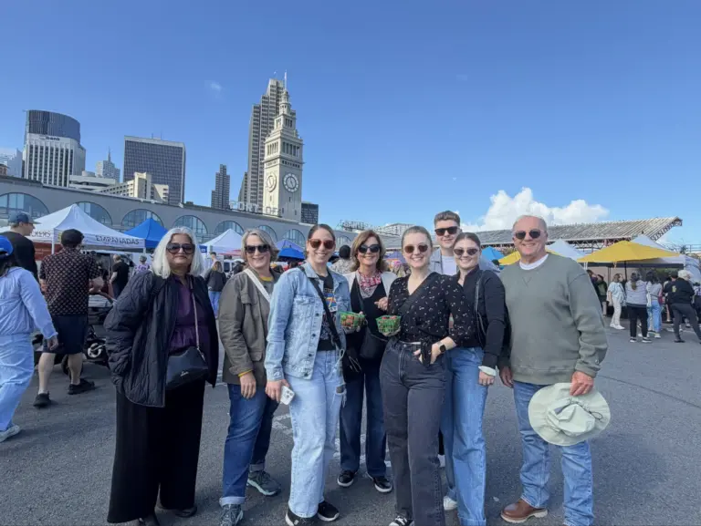 A family on an Edible Excursions food tour pose in front of the Ferry Building