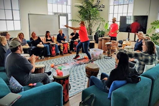 Coworkers join a drum circle with led by the folks at Drummm