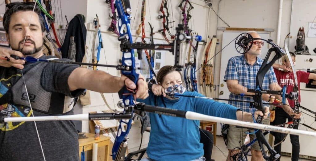 Teammates learn how to pull a bow in a Palomo Archery class