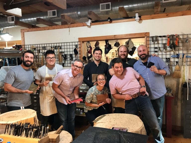 A team poses together after a successful leather working class at Chicago School of Shoemaking