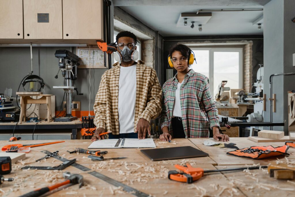 Two team members pose in a woodworking studio