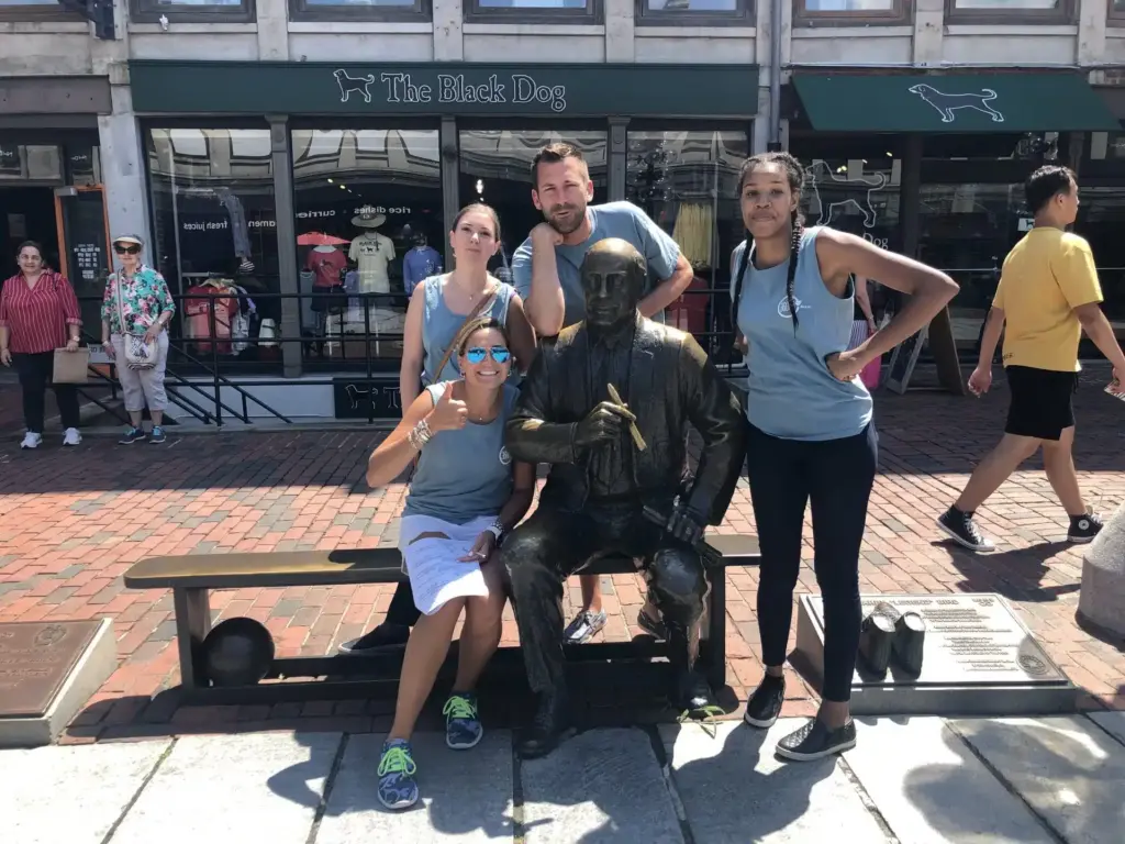 A team on a scavenger hunt pose by an iconic Boston sculpture