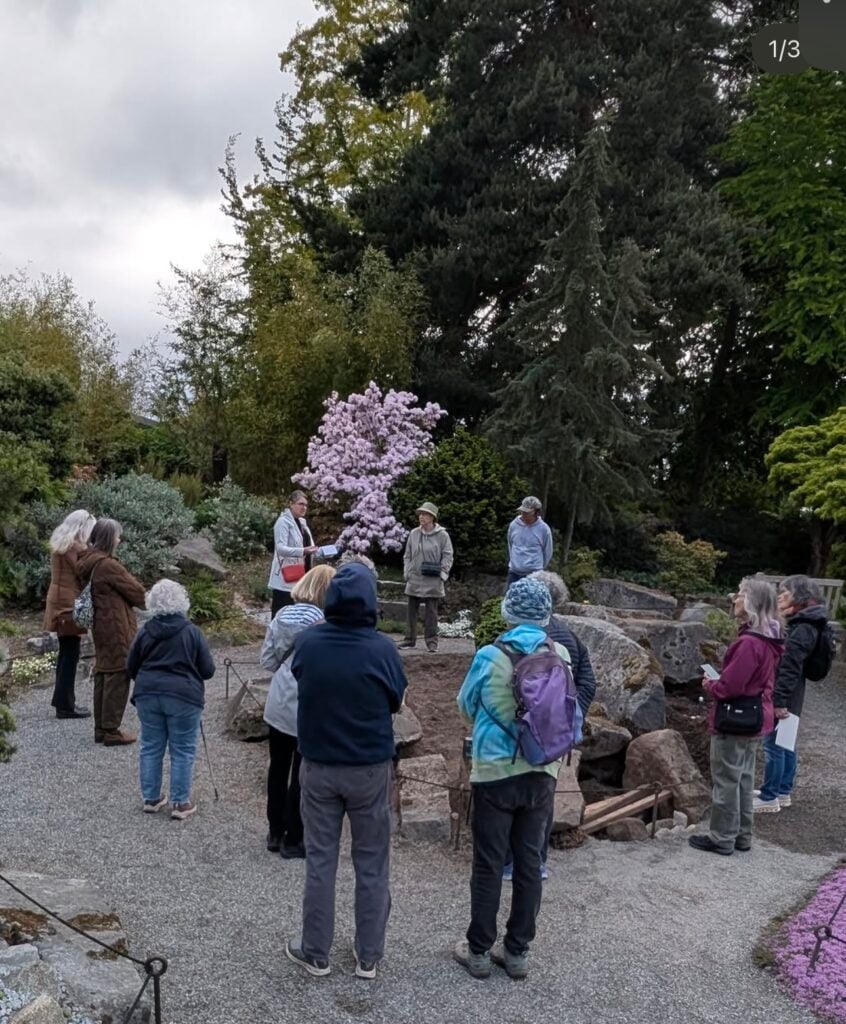 Team member gather around a tour guide in the Bellevue Botanical Gardens