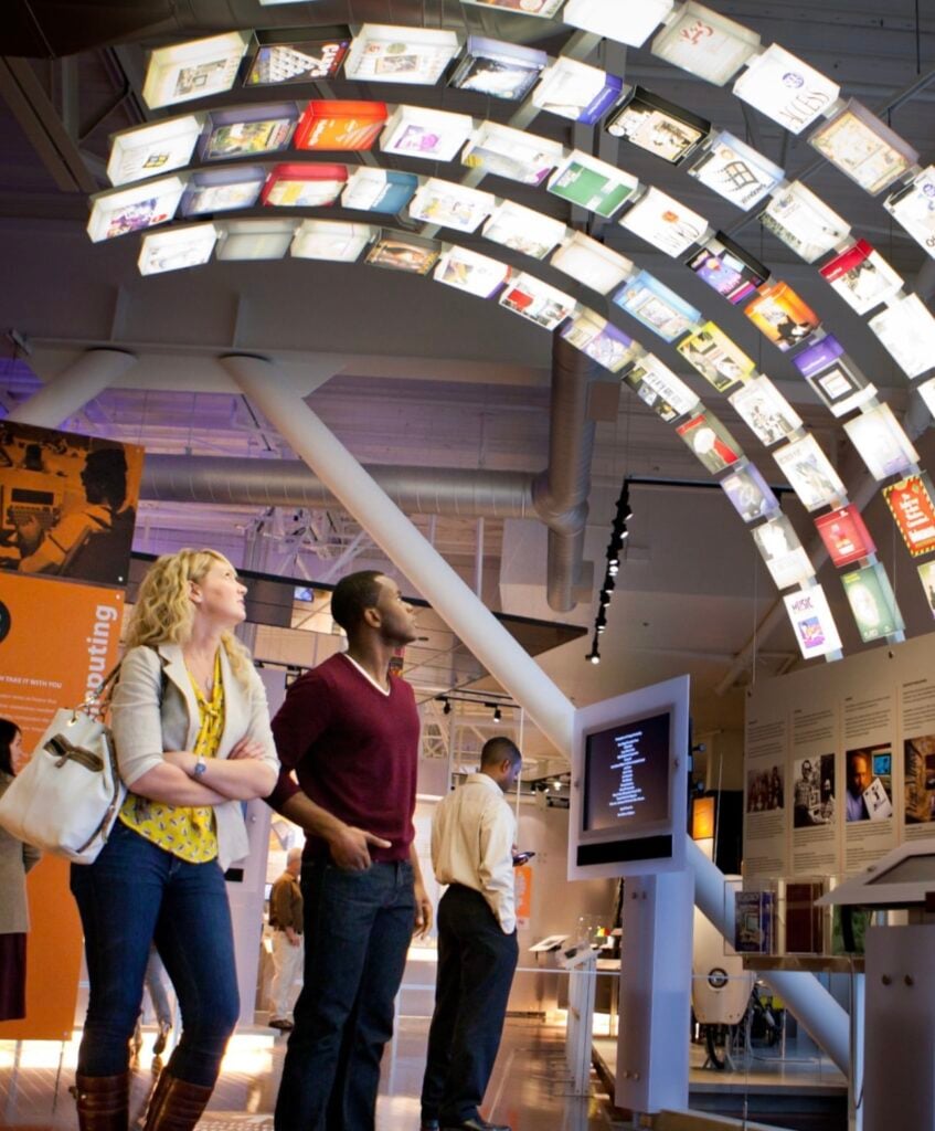 Two people look up at an electronic display at the Computer History Museum