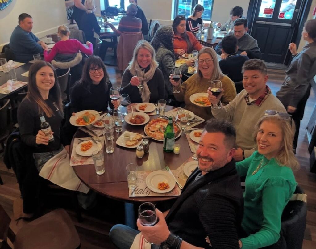 Smiling team members sit around a table of food on a Georgetown Food Tour