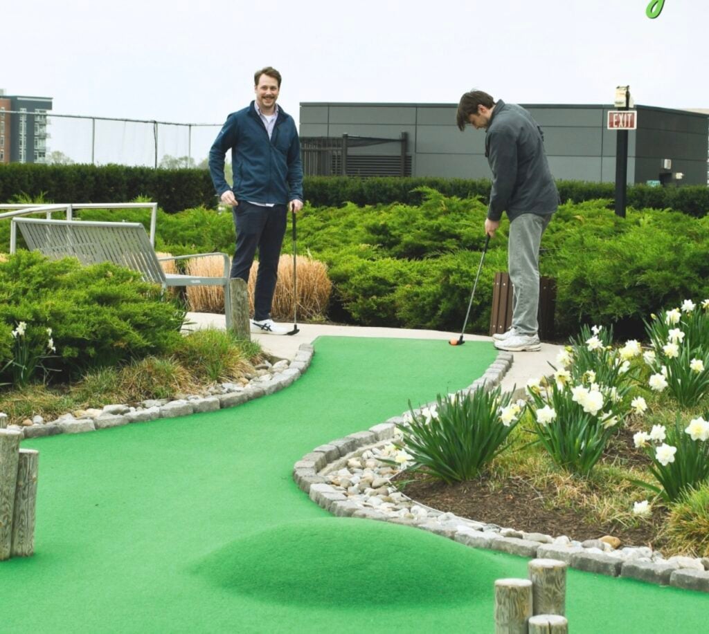 Two men look at the green as they play mini golf at Perch Putt