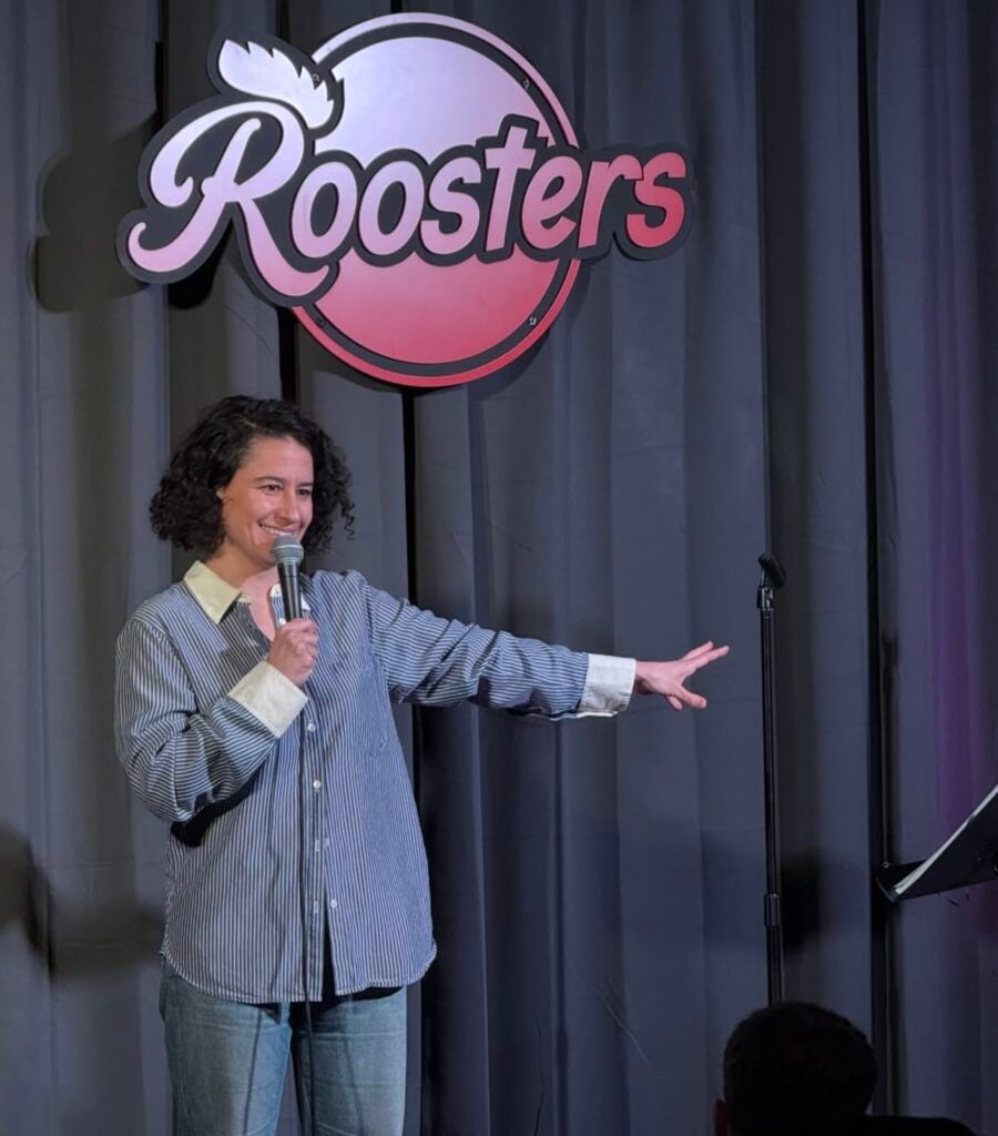 A comedian points to the left on the Roosters stage