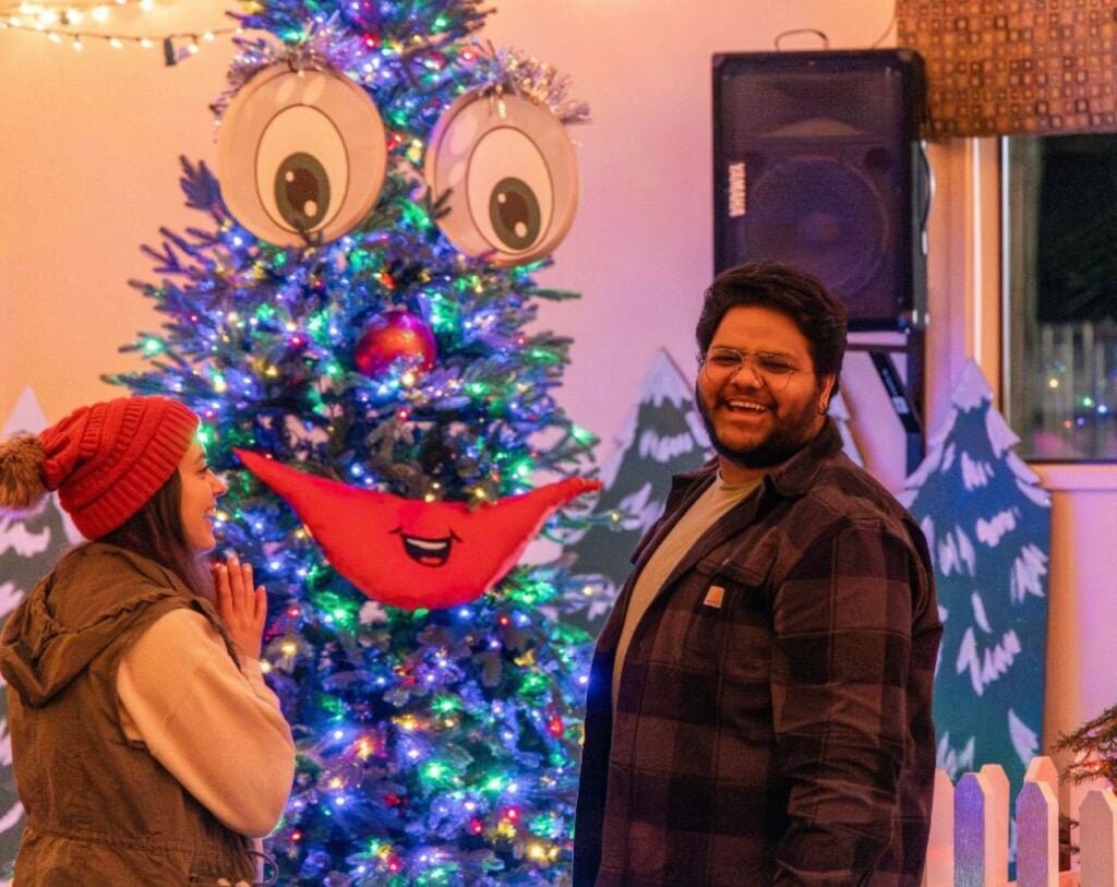 A smiling christmas tree next to a smiling man at The Lights of Christmas Event