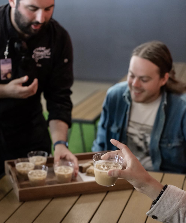 Teammates on an Eat Seattle food tour are delivered cups with drinks to try as they smile
