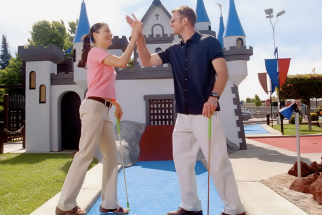 Coworkers high five in front of a castle at Golfland