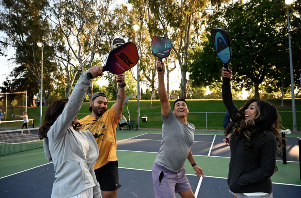 Team mates raise their Pickleball raquets high as they celebrate their win