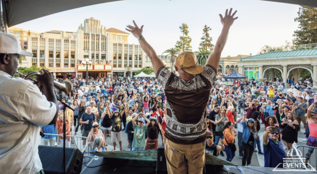 Crowds celebrate a jubilant performer after an awesome musical performance in the square of Redwood City