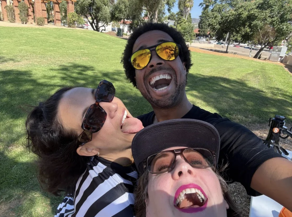 Three coworkers smile in front of a scavenger hunt clue