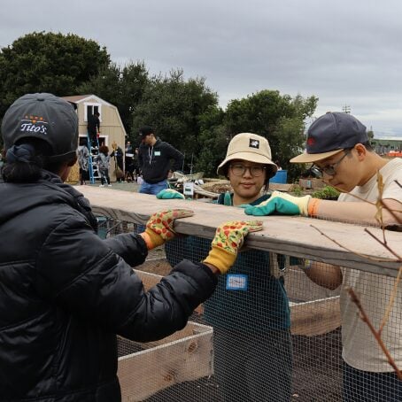 Team members lift a wooden beam together