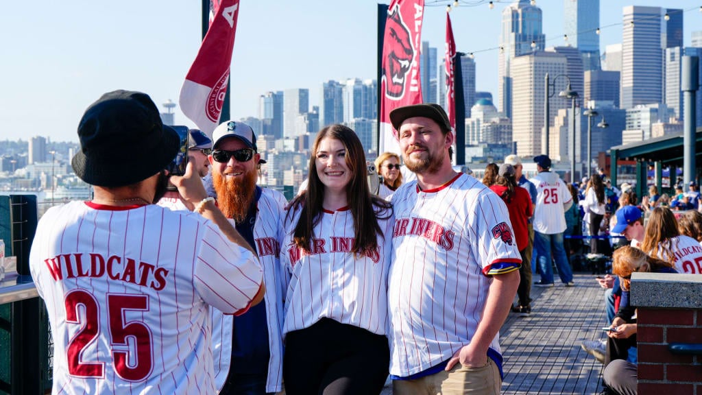 Mariners fans pose outside the stadium wearing their teams colors