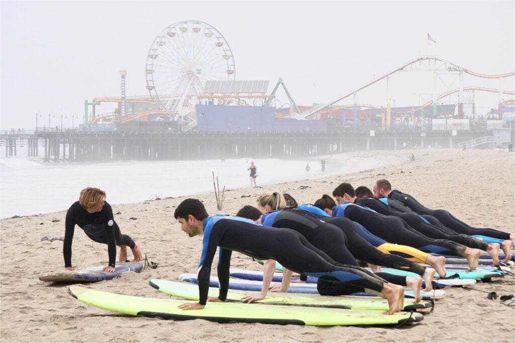 Team members learn surfing basics on the beach
