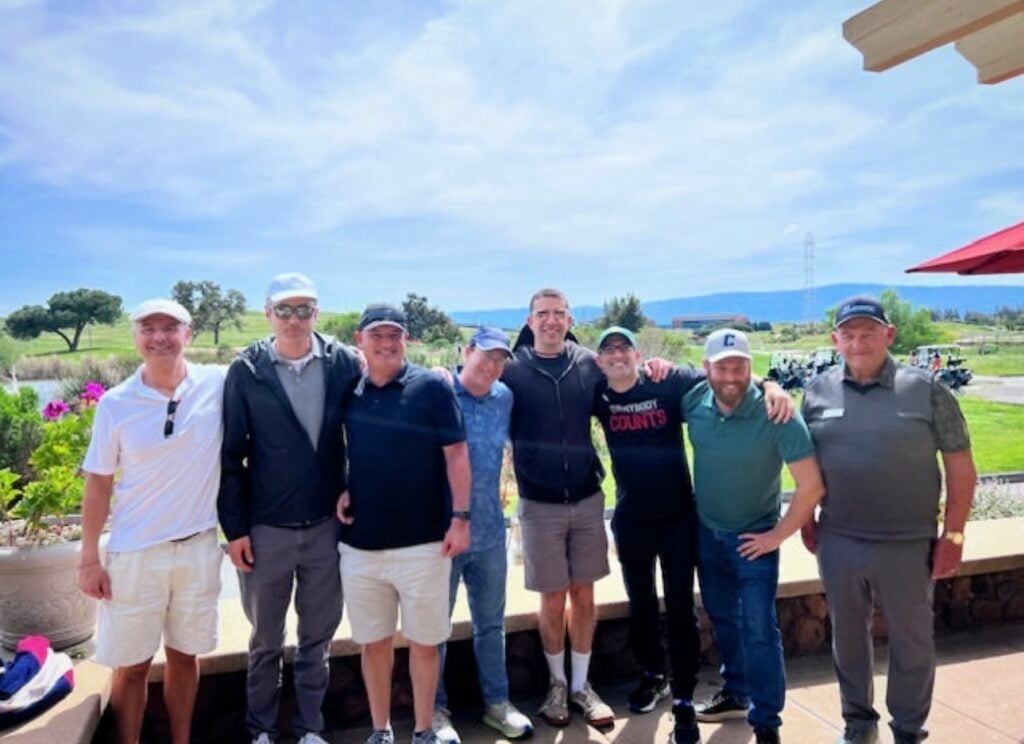 A large team poses in front of the Shoreline Golf Links course