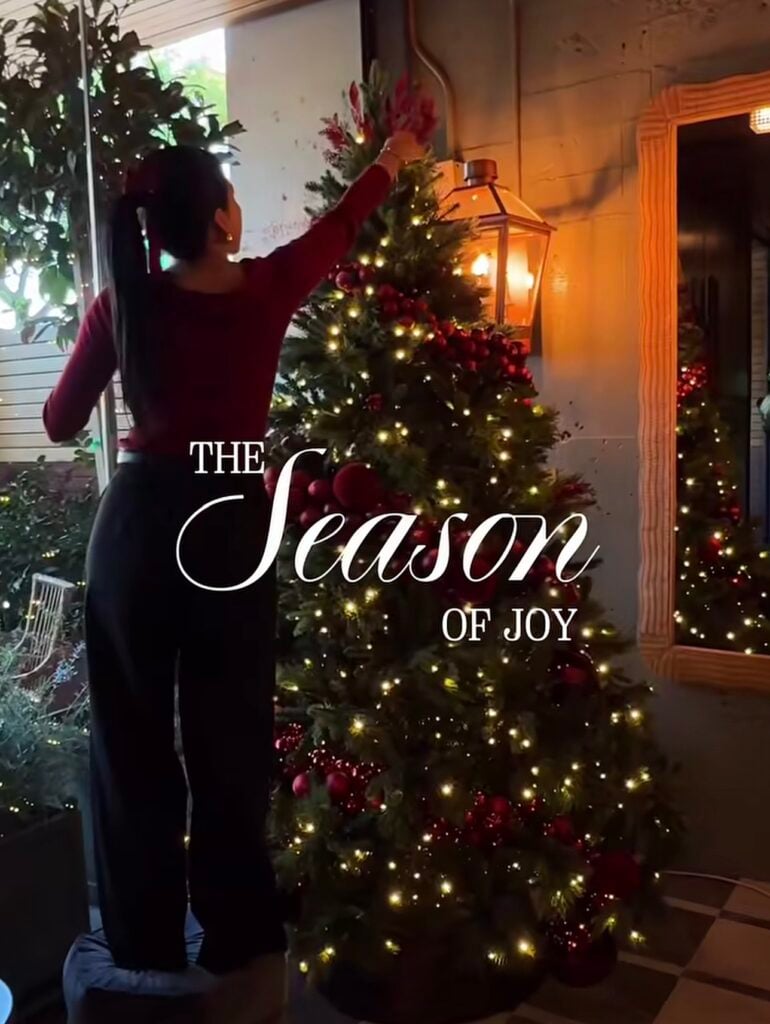 text saying the season of joy overtop the imag eof a woman hanging ornaments on the tree