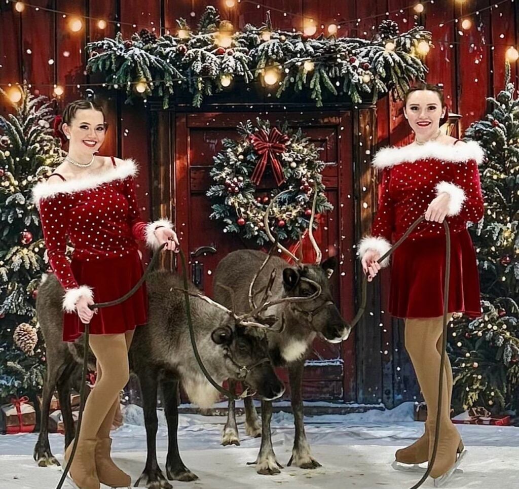 two girls dressed in festive colors next to a reindeer