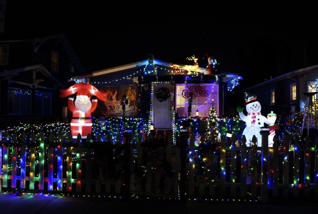 A hous eis decked out in christmas lights and inflatable Santas